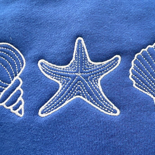 A blue sweatshirt with a design of seashells and a starfish on the front.