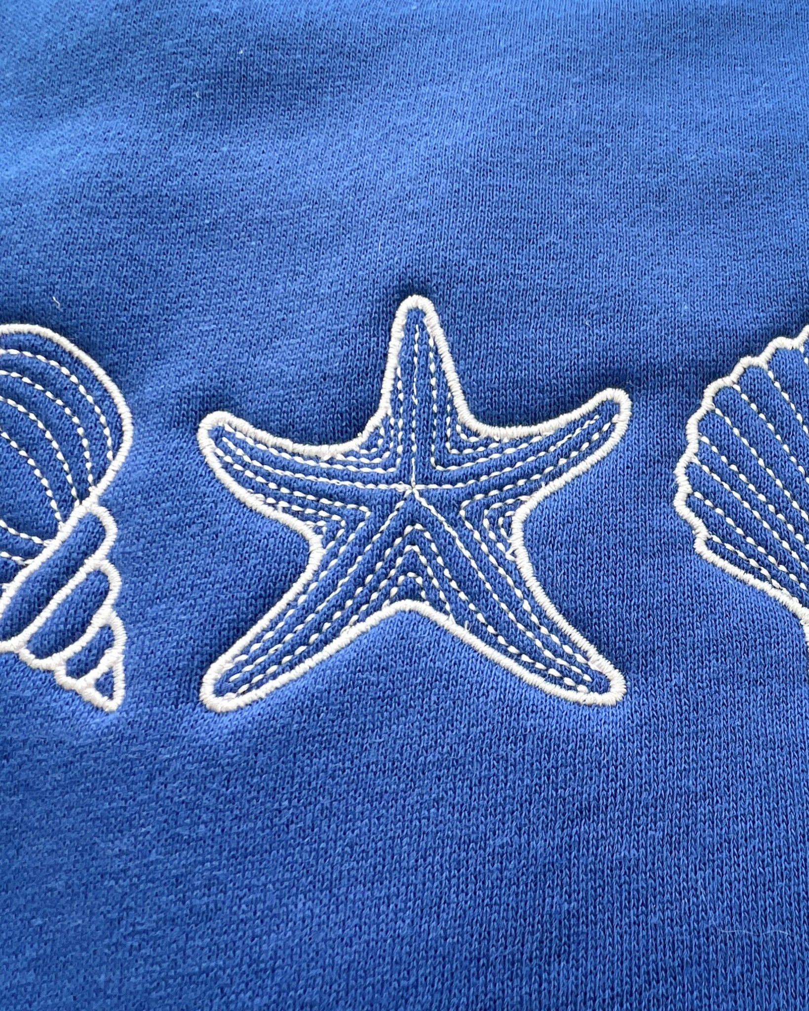 A blue sweatshirt with a design of seashells and a starfish on the front.
