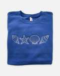 Folded blue sweatshirt with white shell and starfish designs on a white background