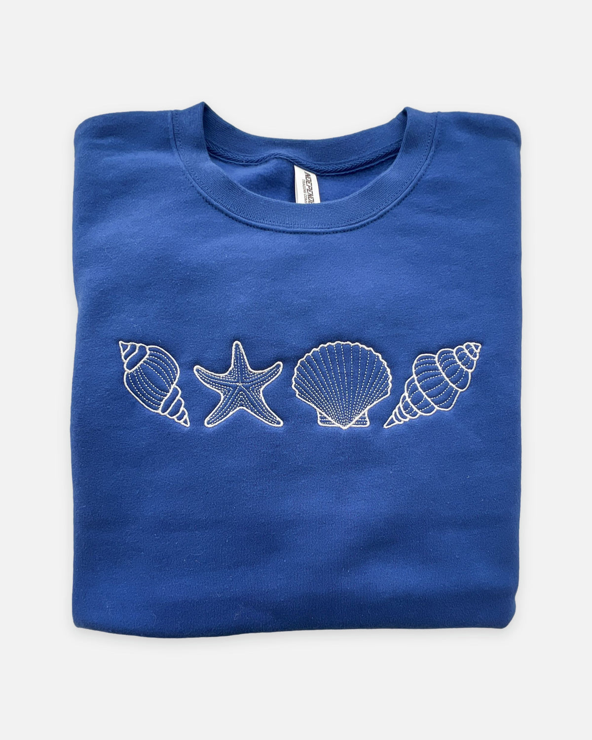 Folded blue sweatshirt with white shell and starfish designs on a white background